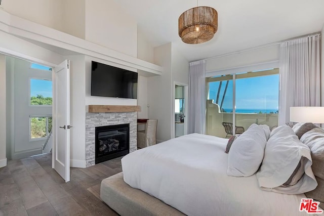 bedroom featuring wood-type flooring and a stone fireplace