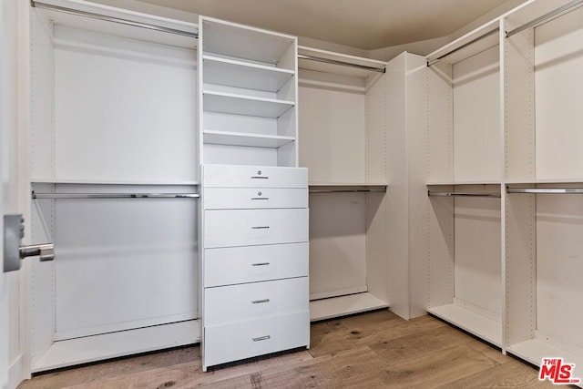 walk in closet with light hardwood / wood-style floors