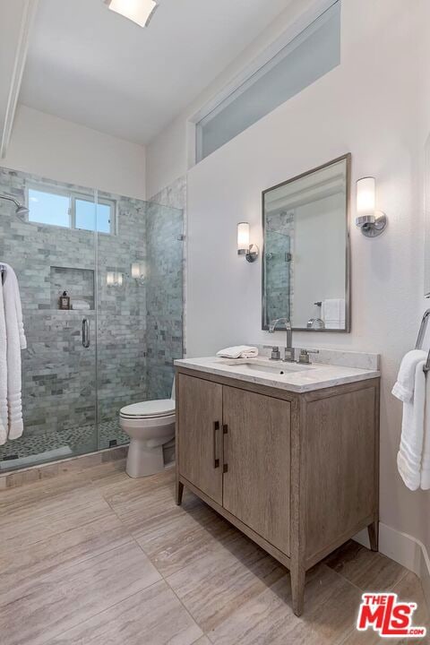 bathroom featuring vanity, toilet, and an enclosed shower