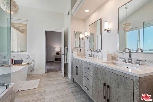 bathroom with tiled bath, hardwood / wood-style floors, and vanity