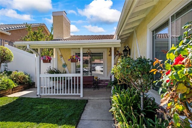 property entrance with covered porch and a yard