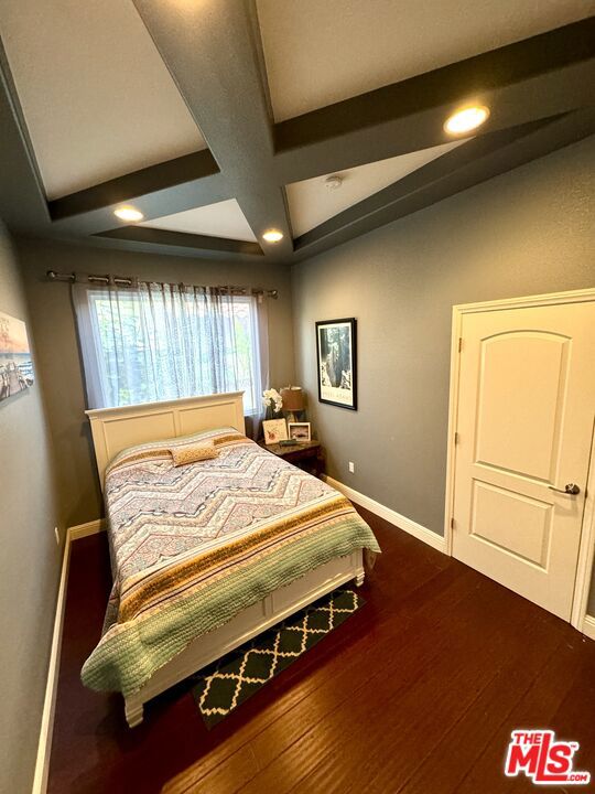 bedroom featuring coffered ceiling, beamed ceiling, and hardwood / wood-style flooring