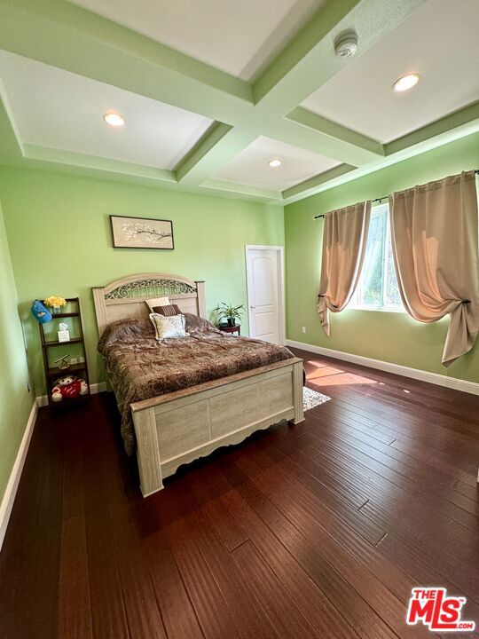 bedroom with coffered ceiling, dark hardwood / wood-style flooring, and beamed ceiling