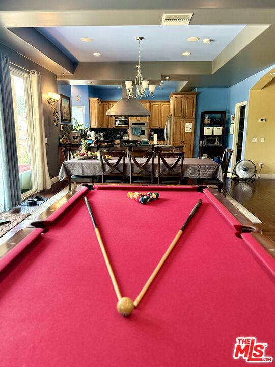 playroom with billiards, hardwood / wood-style floors, a chandelier, and a tray ceiling