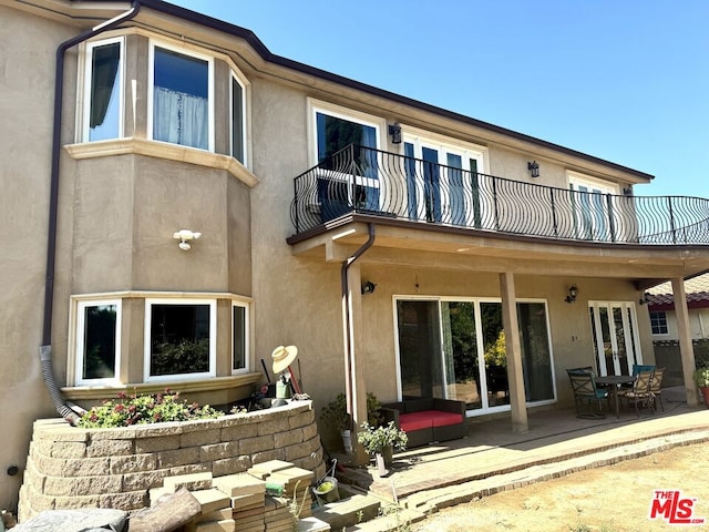 rear view of property with a balcony and a patio