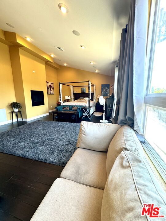 living room featuring vaulted ceiling, a fireplace, and dark hardwood / wood-style flooring