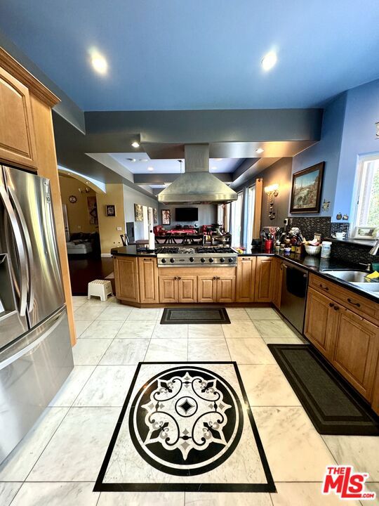 kitchen featuring black dishwasher, kitchen peninsula, island range hood, sink, and stainless steel fridge with ice dispenser