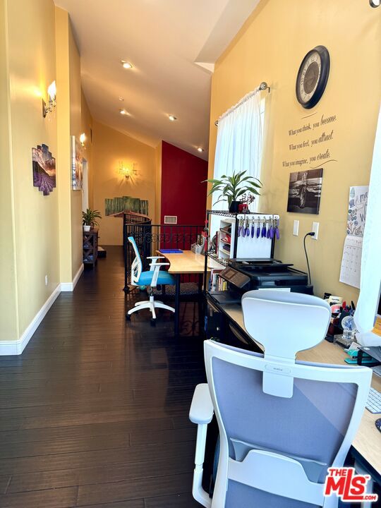 home office featuring vaulted ceiling and dark wood-type flooring