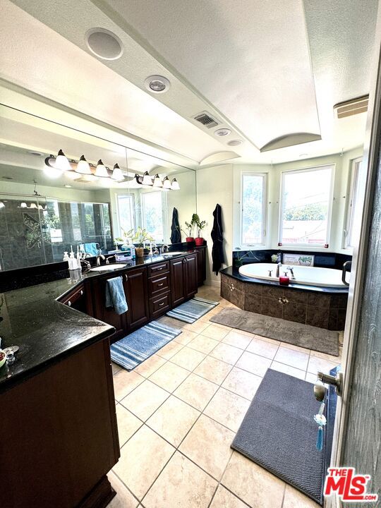 bathroom with shower with separate bathtub, tile patterned floors, a textured ceiling, and vanity