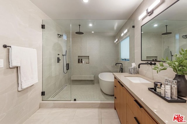 bathroom featuring vanity, tile walls, shower with separate bathtub, and tile patterned floors