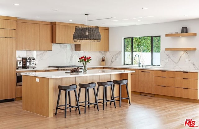 kitchen featuring decorative backsplash, light hardwood / wood-style floors, a kitchen island, and a breakfast bar area