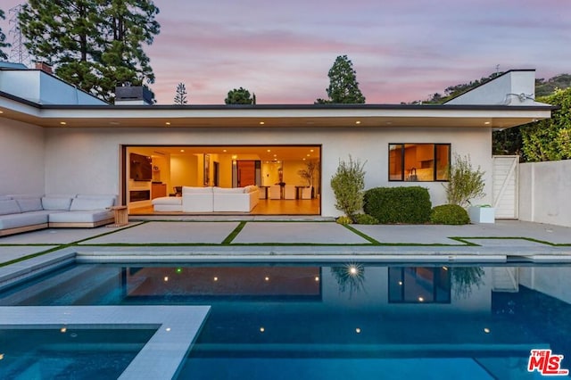 back house at dusk with outdoor lounge area and a patio area