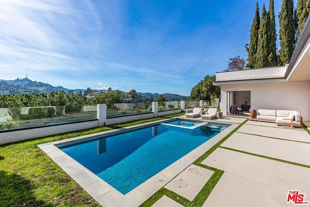 view of swimming pool with an outdoor living space, a mountain view, and a patio area