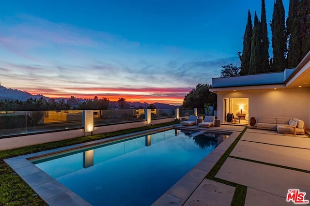 pool at dusk featuring an outdoor hangout area and a patio area