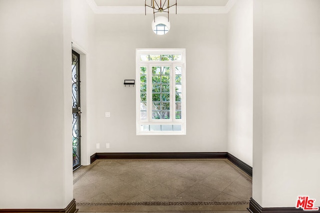 empty room with crown molding and a chandelier