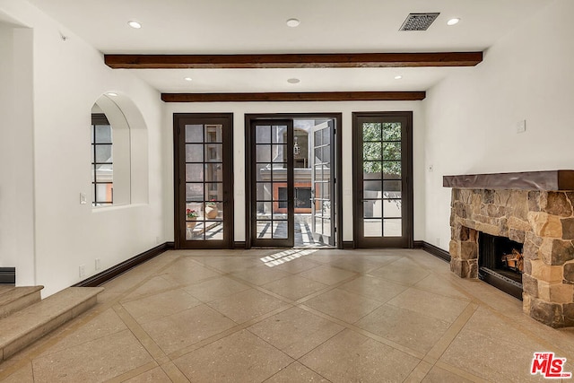 unfurnished living room with a fireplace and beam ceiling