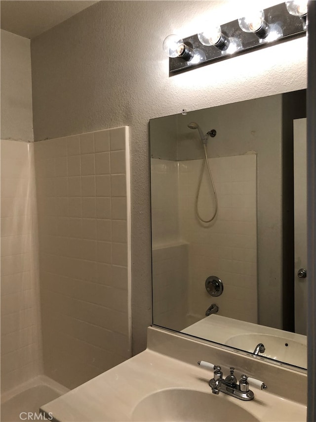 bathroom with tiled shower / bath and vanity