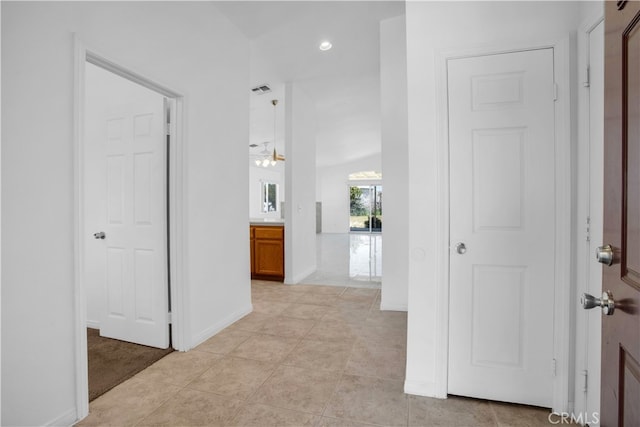 corridor featuring lofted ceiling, a chandelier, and light tile patterned flooring