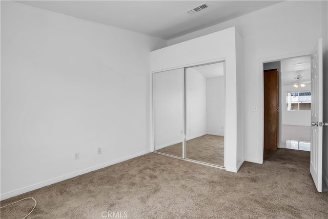 unfurnished bedroom with light colored carpet and a closet