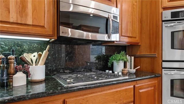 kitchen with tasteful backsplash, dark stone countertops, and stainless steel appliances