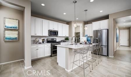 kitchen with hanging light fixtures, white cabinetry, an island with sink, and appliances with stainless steel finishes