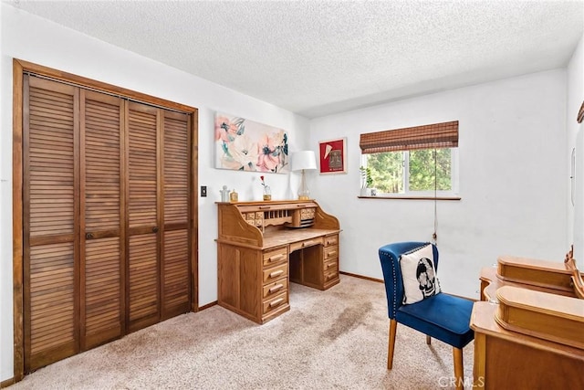 office space featuring a textured ceiling, light colored carpet, and baseboards