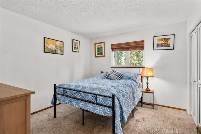 bedroom with a closet, carpet flooring, baseboards, and a textured ceiling