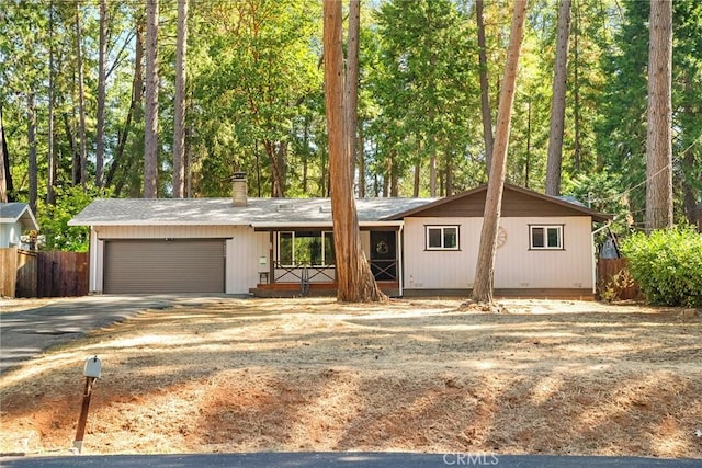 single story home featuring driveway, a chimney, fence, and an attached garage