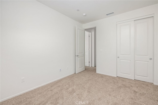 unfurnished bedroom featuring light colored carpet and a closet