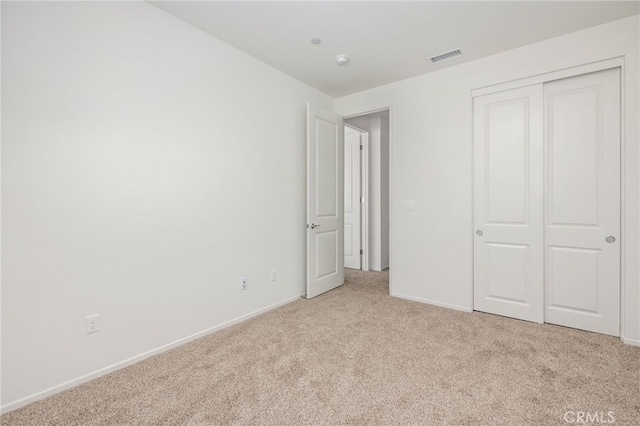 unfurnished bedroom featuring light colored carpet and a closet