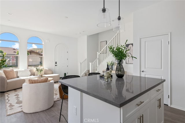 kitchen featuring pendant lighting, dark stone counters, white cabinetry, and dark wood-type flooring