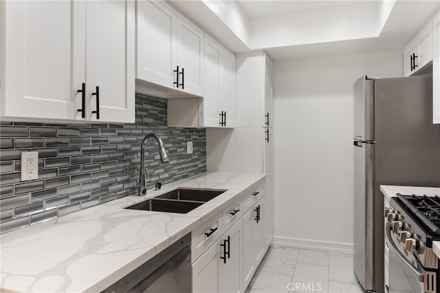 kitchen with sink, backsplash, white cabinetry, stainless steel stove, and light stone countertops