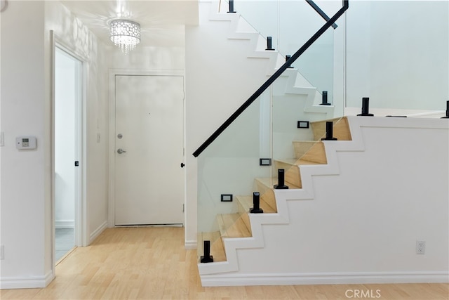 stairs with wood-type flooring and a chandelier