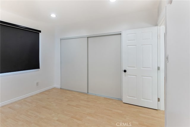 unfurnished bedroom featuring light hardwood / wood-style flooring and a closet