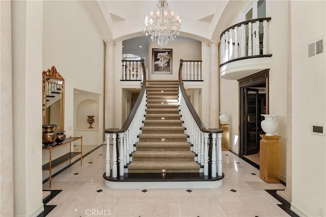 stairway featuring a chandelier, a towering ceiling, and decorative columns