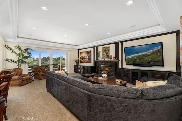 carpeted living room with crown molding, a fireplace, and a raised ceiling