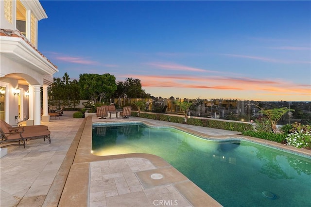 pool at dusk with a patio area