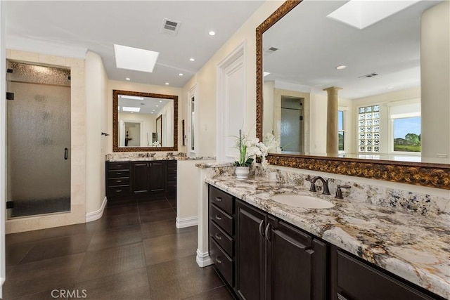 bathroom with vanity, a skylight, and a shower with door