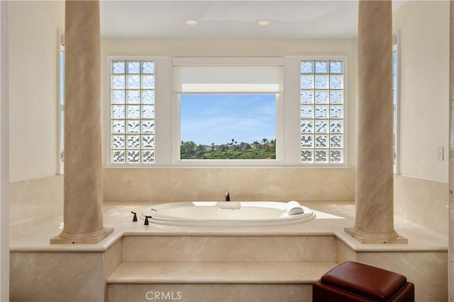 bathroom with tiled bath and ornate columns