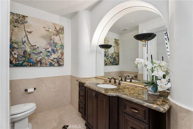 bathroom with tile walls, toilet, and vanity