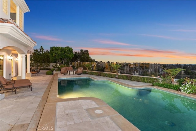 pool at dusk with a patio area