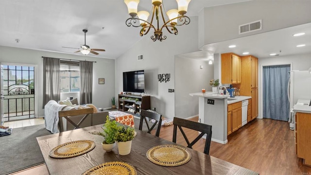 dining area featuring ceiling fan with notable chandelier, hardwood / wood-style floors, sink, and high vaulted ceiling