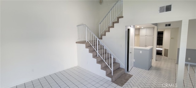 stairway featuring a towering ceiling and tile patterned flooring