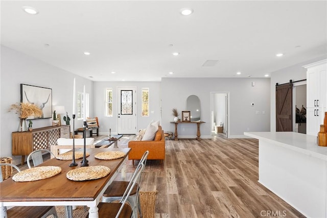 dining space featuring a barn door and light hardwood / wood-style flooring