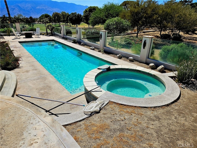 view of pool featuring an in ground hot tub, a mountain view, and a patio area