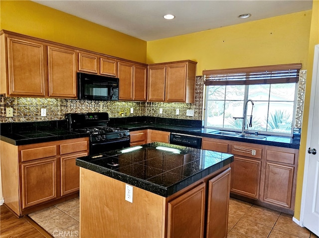 kitchen featuring decorative backsplash, black appliances, sink, and a kitchen island