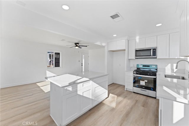 kitchen with white cabinetry, sink, ceiling fan, stainless steel appliances, and light hardwood / wood-style flooring