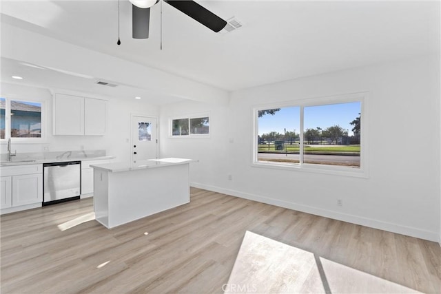 kitchen with sink, stainless steel dishwasher, light wood-type flooring, a kitchen island, and white cabinetry