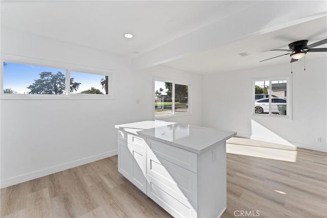 kitchen featuring white cabinets, ceiling fan, a center island, and light wood-type flooring