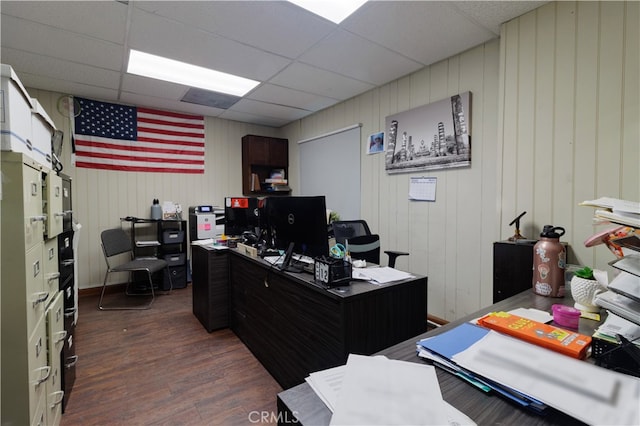 office area featuring wooden walls, a drop ceiling, and dark hardwood / wood-style flooring